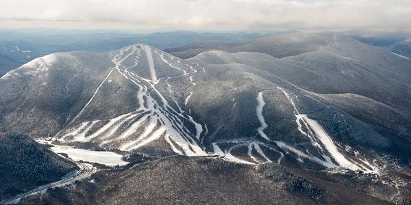 Aerial view of snow-covered ski trails on mountainous terrain.