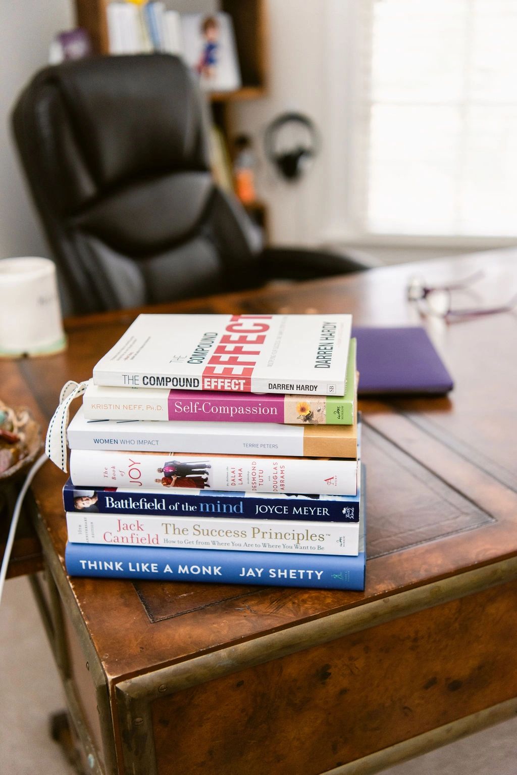 Books on desk. Compound effect, Self compassion, the book of joy, battlefield of the mind, 