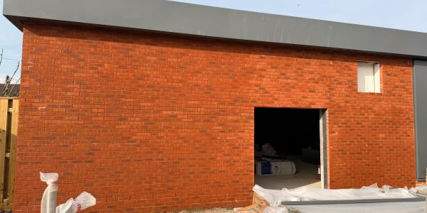 New brick building under construction with open doorway.