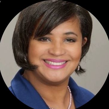 Smiling woman with short hair wearing a blue blazer and pink lipstick.