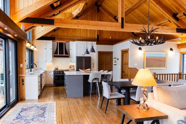 Cozy open-concept kitchen and living area with wooden beams and natural light.