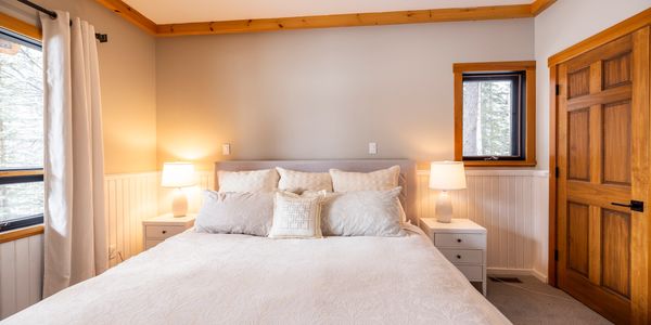 Cozy bedroom with white bedding and wooden accents.