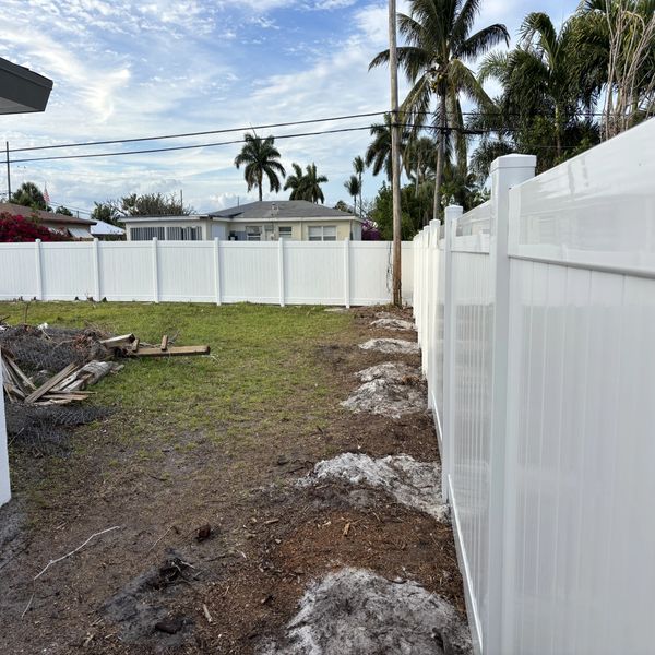 Removal of old wood fencing and posts, new fence installation, removal of bushes, and trimmed tree branches.