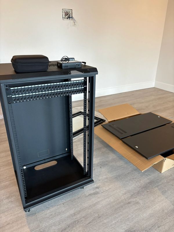 Empty server rack with panels on the floor nearby.