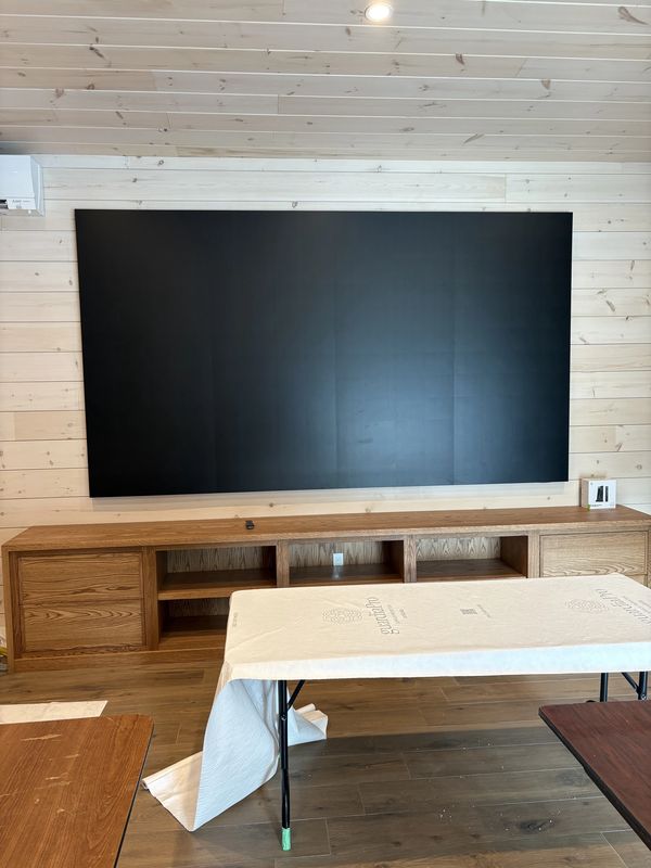 Minimalist living room with large black wall art and wooden furniture.