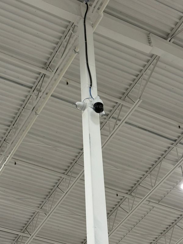 Security cameras mounted on a white pillar in a large indoor space.