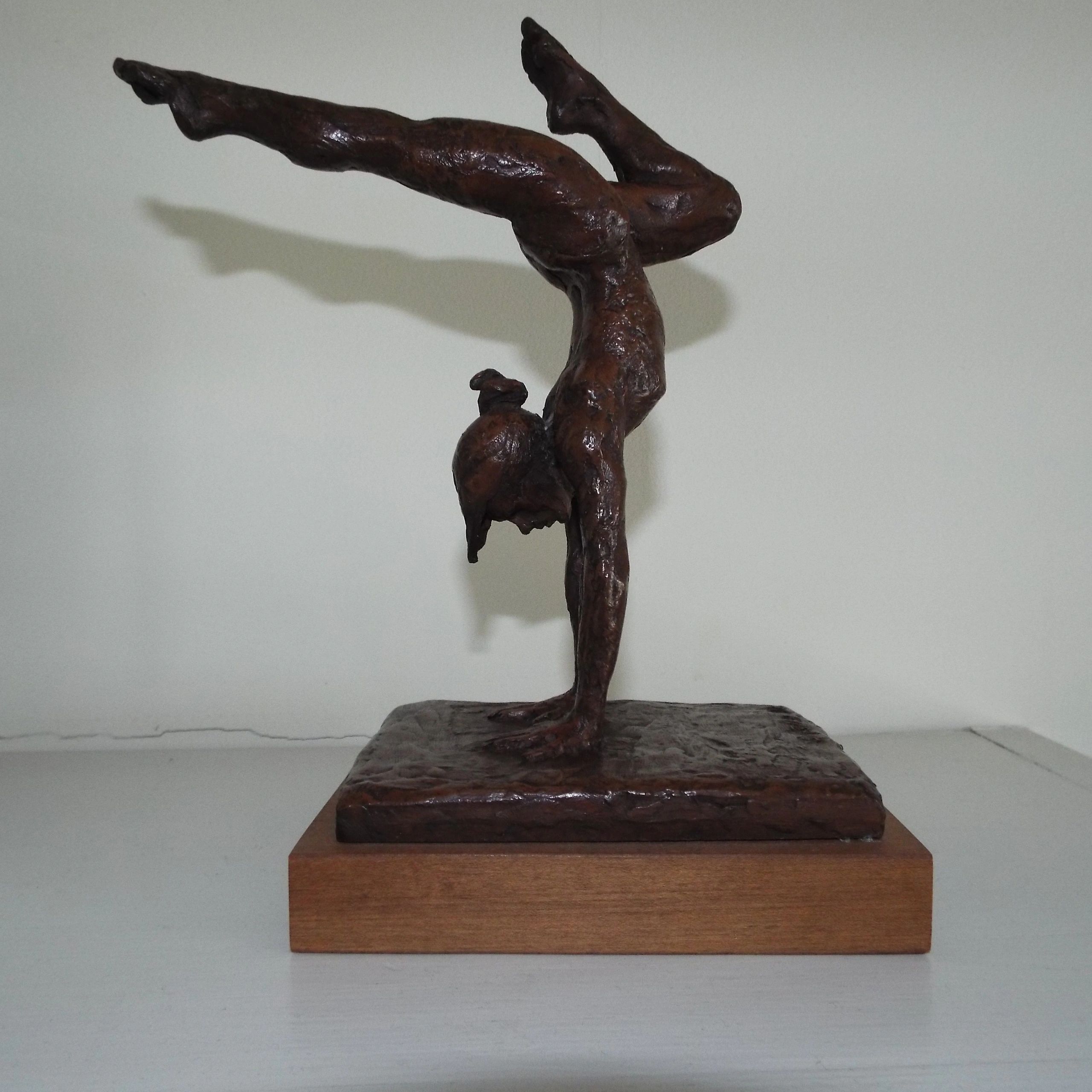 Bronze sculpture of a person performing a handstand.