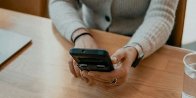 Person using a smartphone at a wooden table.