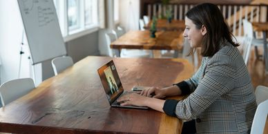 A woman video chatting on a laptop in a bright office.