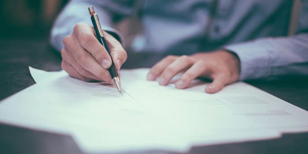 Person signing a document with a pen.