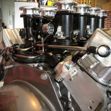 Close-up of a polished engine with multiple carburetors in a workshop.