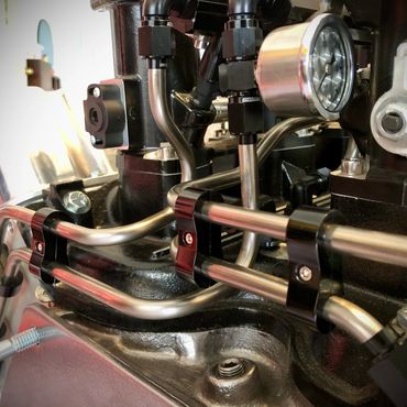 Close-up of engine fuel injection system with metal tubes and gauge.