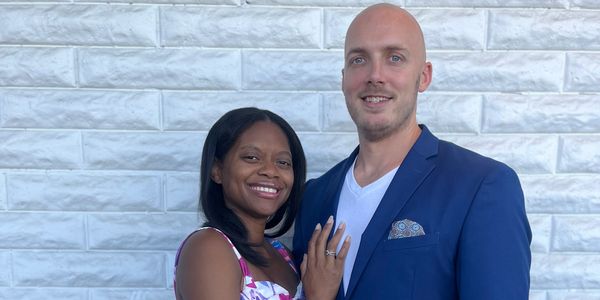 Happy couple posing together, woman showing ring.