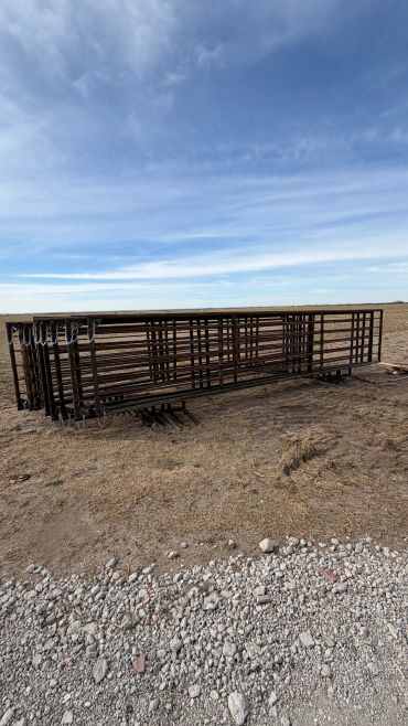 Stacked metal gates on dry ground under a blue sky.