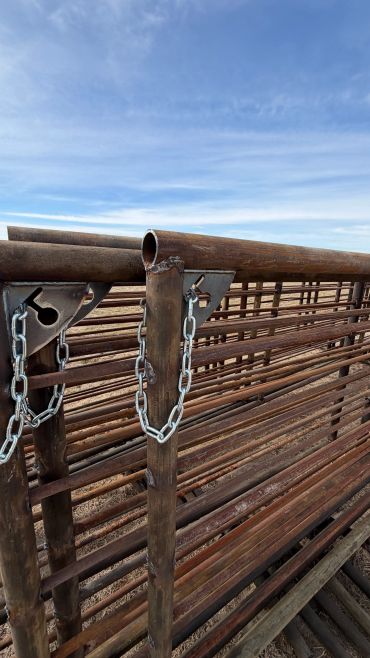 Rusty metal livestock panels chained together outdoors.