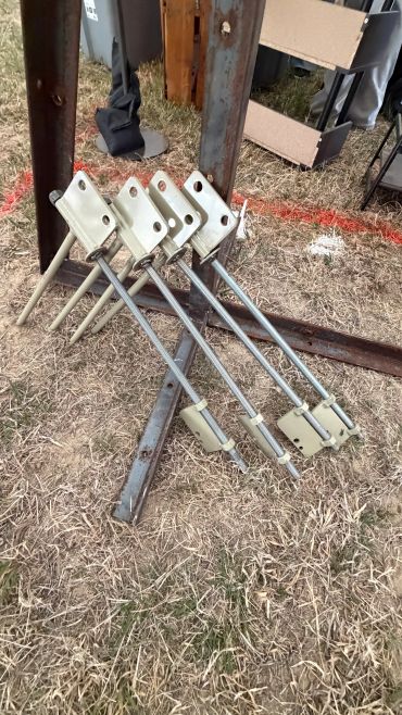Five metal rods with square ends lying on grass.