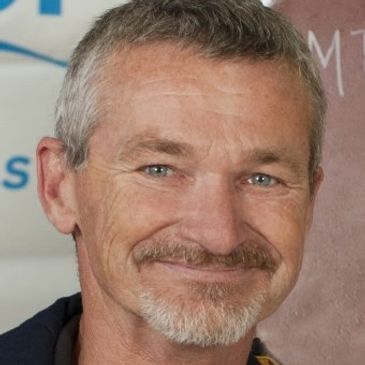 Smiling middle-aged man with gray hair and beard.