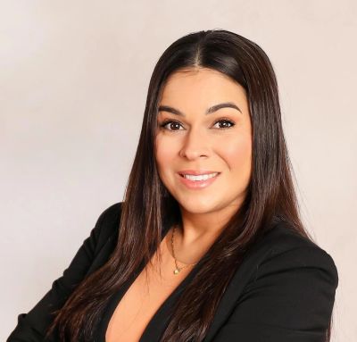 Professional woman smiling with long dark hair in black blazer.