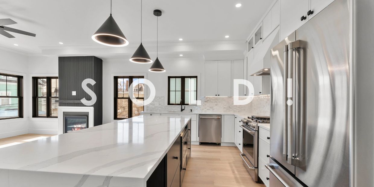 Modern kitchen with sleek white cabinets and stainless steel appliances, labeled as sold.
