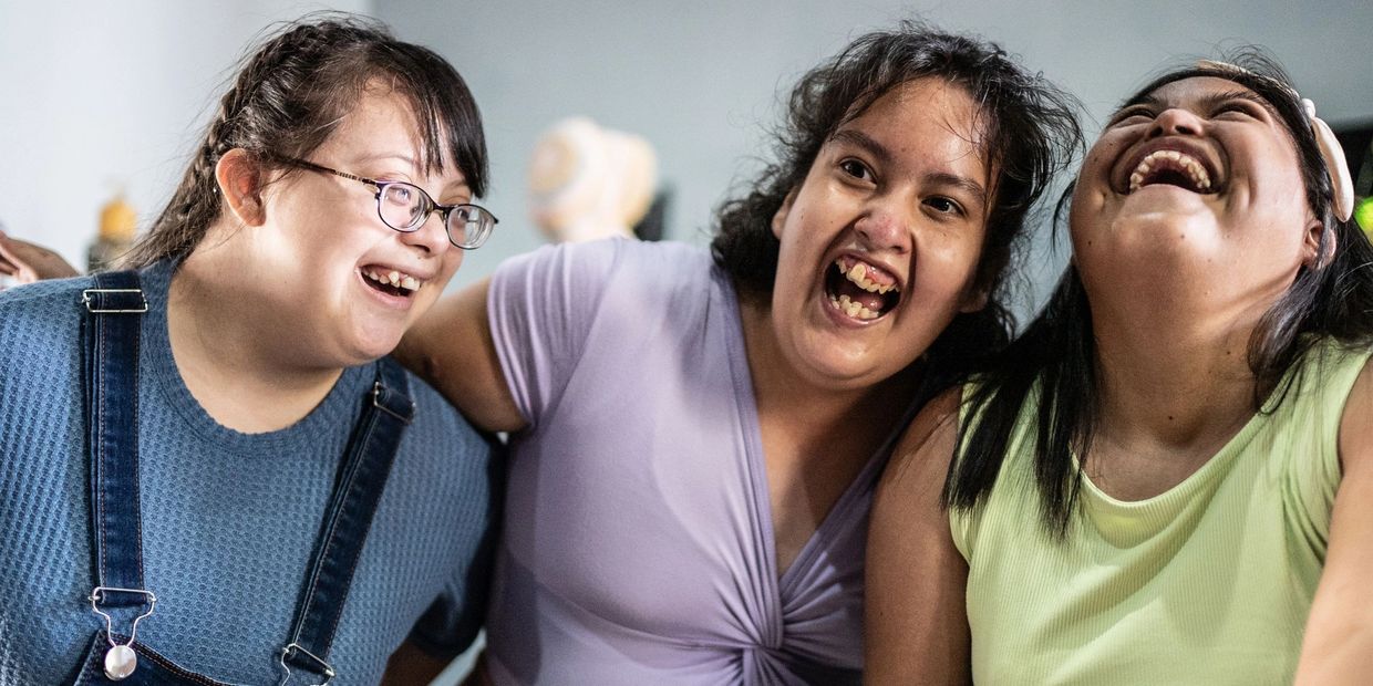 Three women sharing a joyful moment and laughing together indoors.