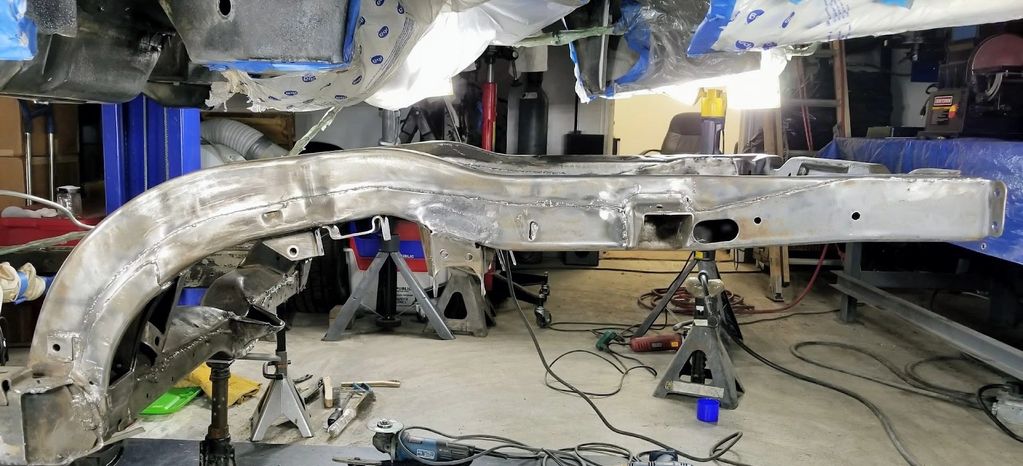 Car frame on jack stands in a workshop.