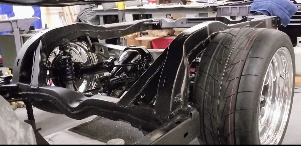 Car chassis with rear suspension and large tire.