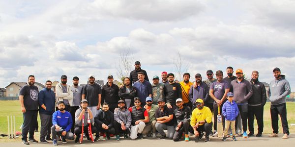Large group of men posing outdoors on a cloudy day.