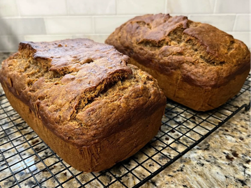 Two freshly baked loaves of bread cooling on a wire rack.