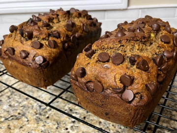 Two freshly baked chocolate chip loaves cooling on a wire rack.