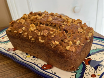 A freshly baked loaf of walnut bread on a decorative plate.