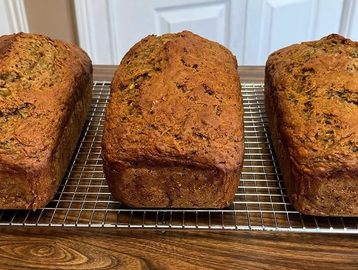 Three freshly baked loaves of bread cooling on a wire rack.