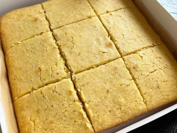 Freshly baked cornbread cut into squares in a baking pan.