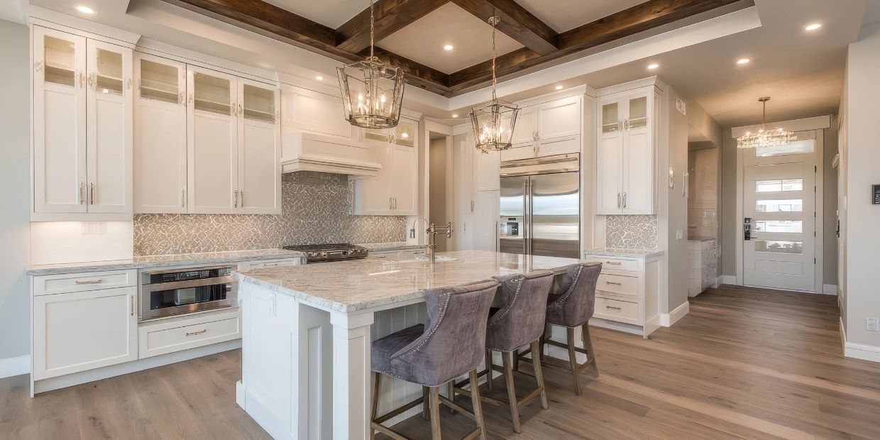 Modern kitchen with white cabinetry, marble island, and wooden ceiling beams.