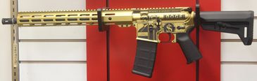 Gold and black modern assault rifle displayed on a rack.