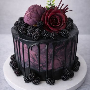 Elegant dark purple cake with blackberries and floral decorations.