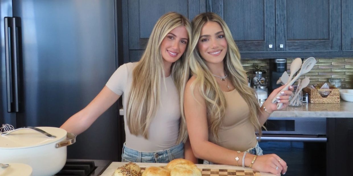 Two smiling women in a kitchen with bread and cooking utensils.
