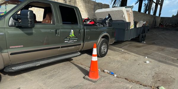 Pickup truck with a trailer full of junk items parked in a warehouse.