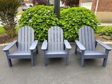 Three blue Adirondack chairs arranged neatly outdoors.