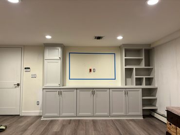 Empty built-in gray cabinetry with shelving and outlet space.