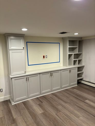 Newly installed white built-in cabinets and shelves in a room with wood flooring.