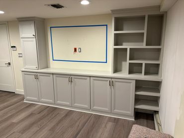 Newly installed white cabinetry with built-in shelves and outlets in a modern room.
