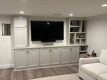 Modern living room with built-in white cabinetry and a wall-mounted flat-screen TV.