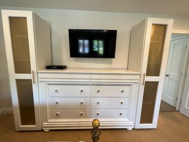 White dresser with two tall cabinets and a mounted TV above.