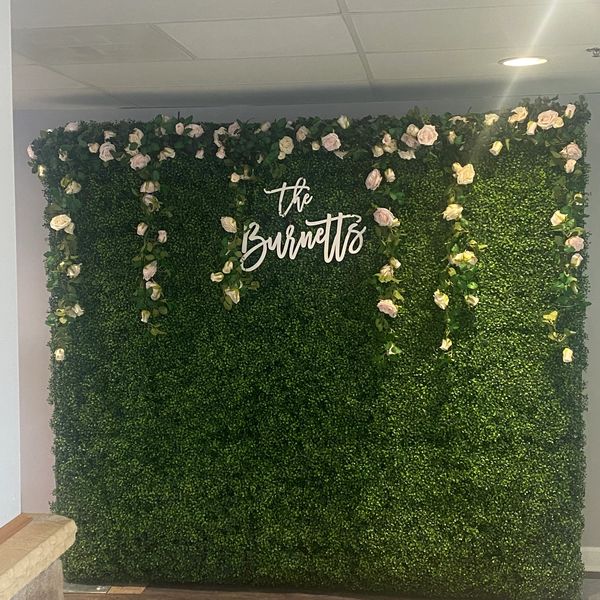 Grass wall with hanging flowers and wood sign 