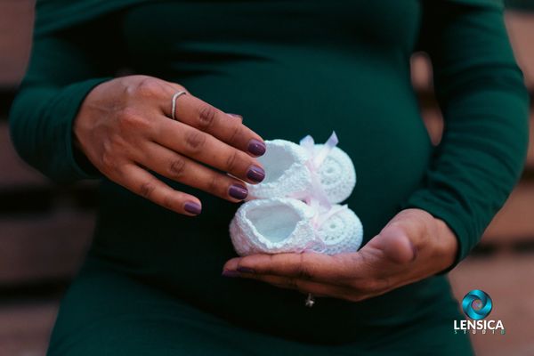 Mom holding tiny baby shoes in front of her baby bump