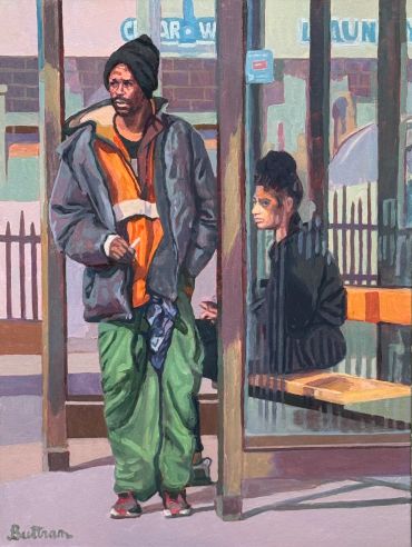 Two people at a bus stop, one standing and one sitting.