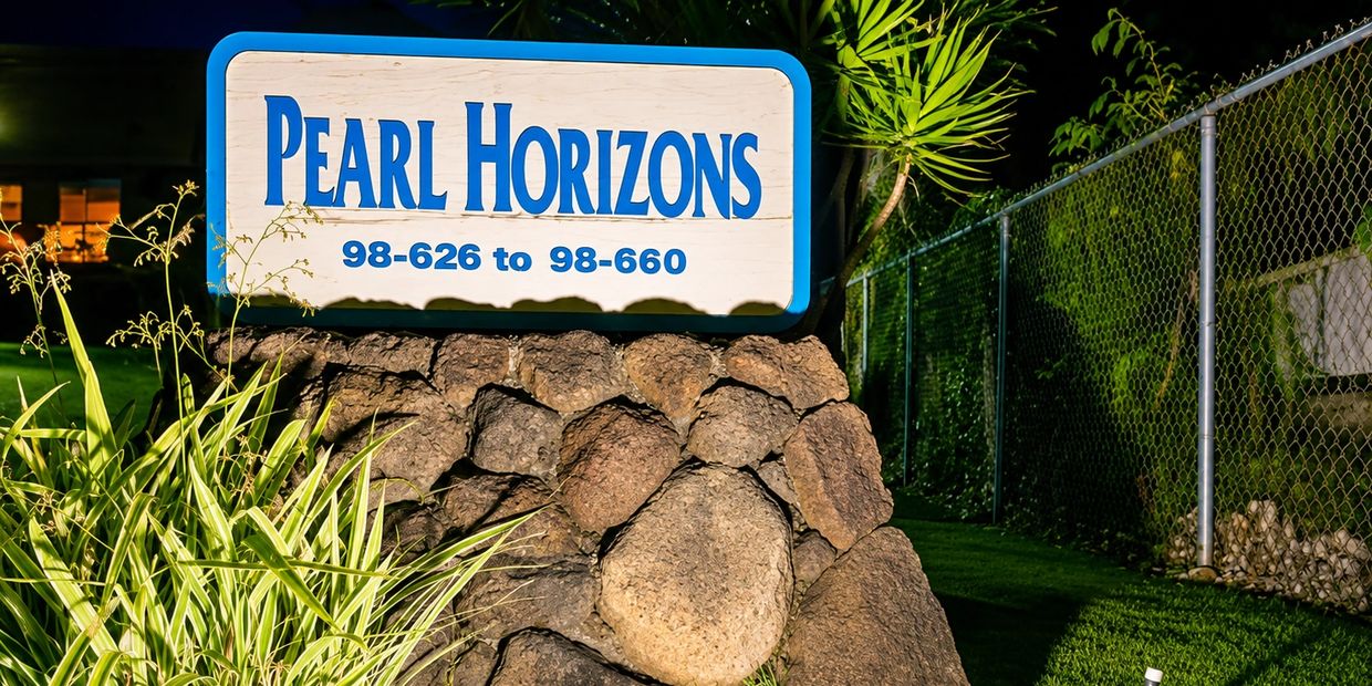 Sign for Pearl Horizons illuminated at night.