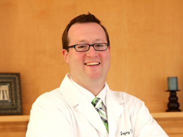 Smiling male doctor in white coat and glasses.