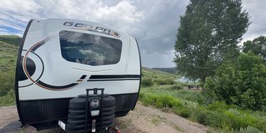 camper with tree and reservoir in background