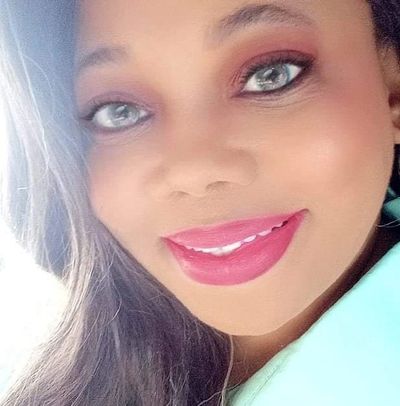Close-up of a smiling woman with bright eyes and pink lipstick.